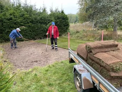 Två medarbetare från Boing All-Service krattar ut jord och förbereder marken inför anläggning av ny gräsmatta.